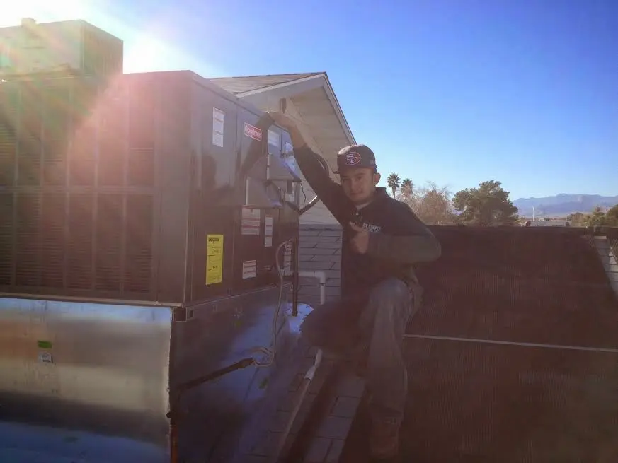 HVAC technician performing AC Tune-Up on a rooftop unit in Bentonville